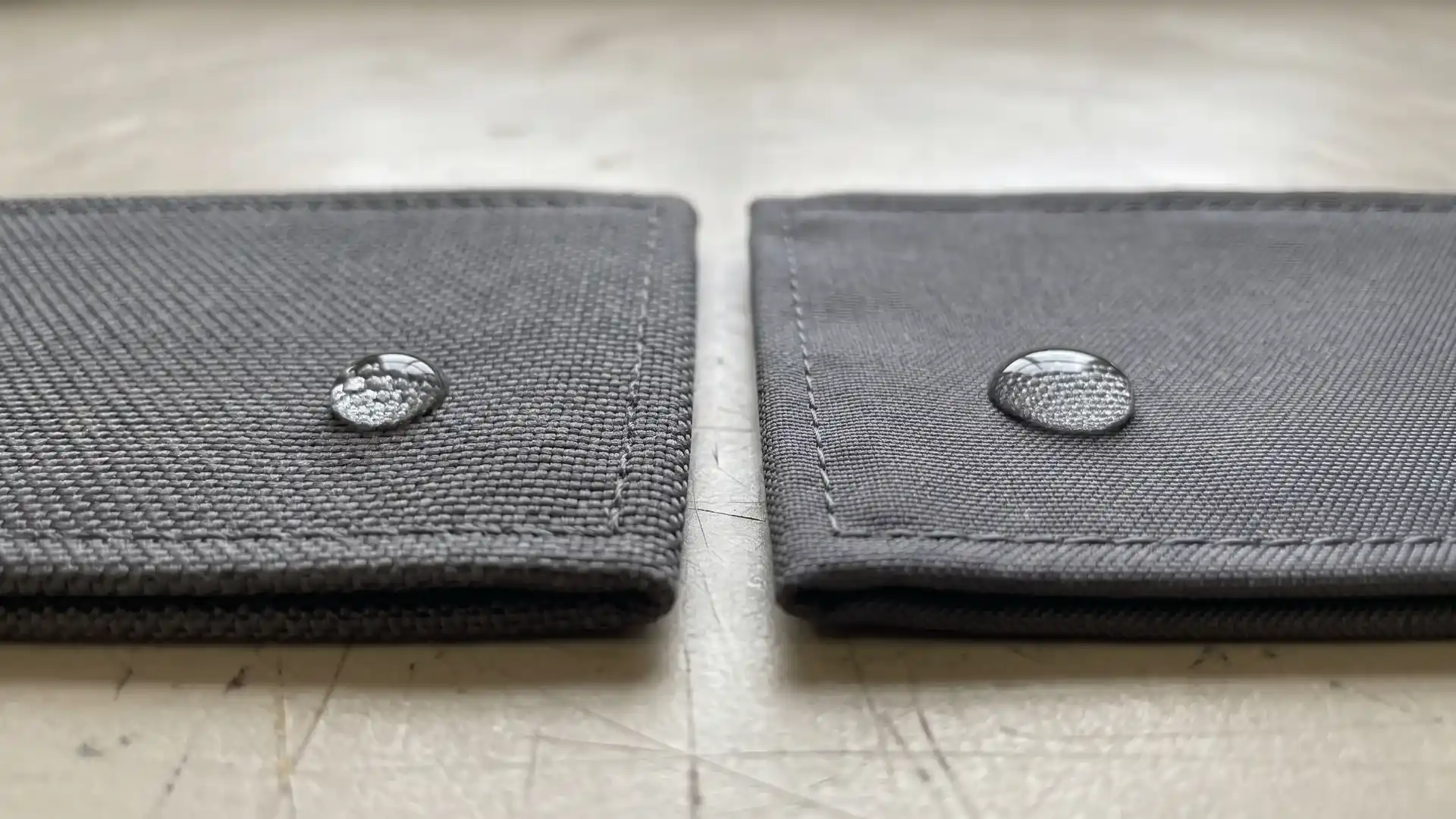 Macro comparison of 1680D high-tenacity nylon and 900D polyester outer shell swatches with stitched edges and water droplets for medical organizer bag fabric selection.
