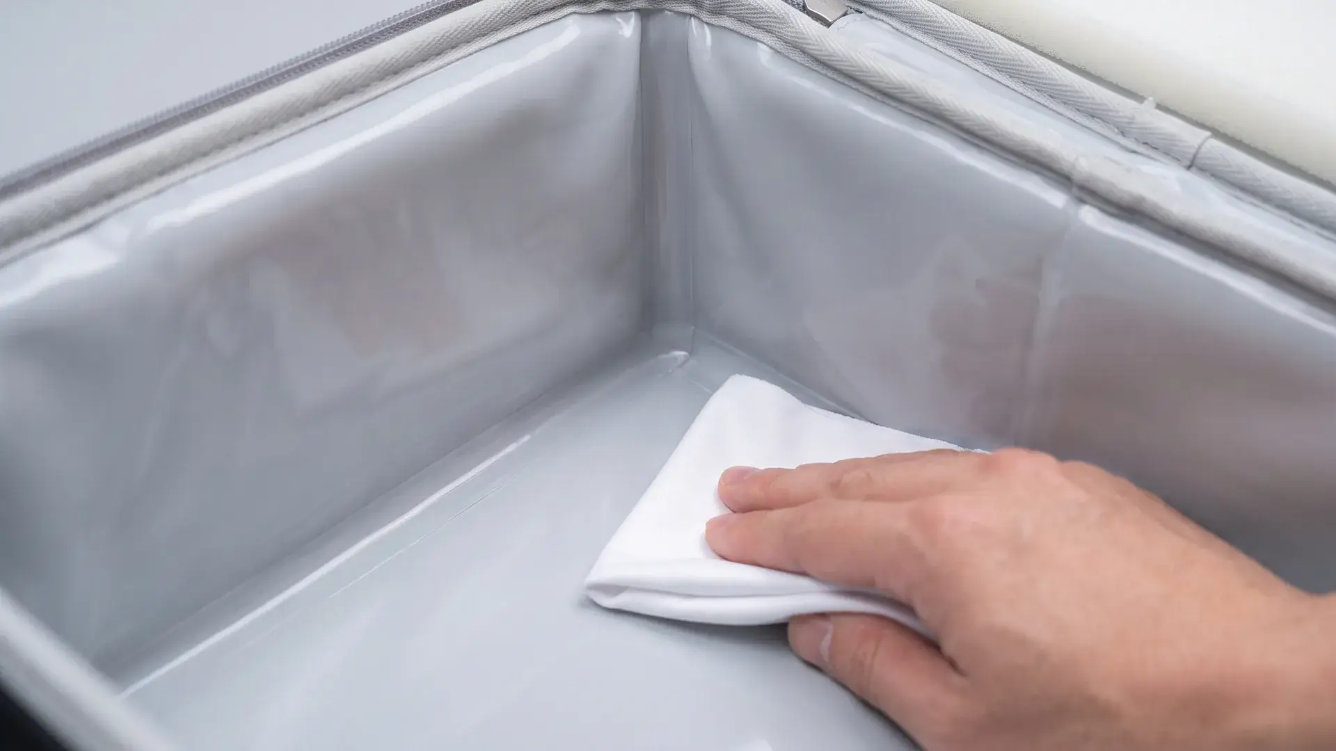 Close-up of a heat-welded TPU liner corner in a cold chain delivery bag being wiped with a sanitizing cloth.