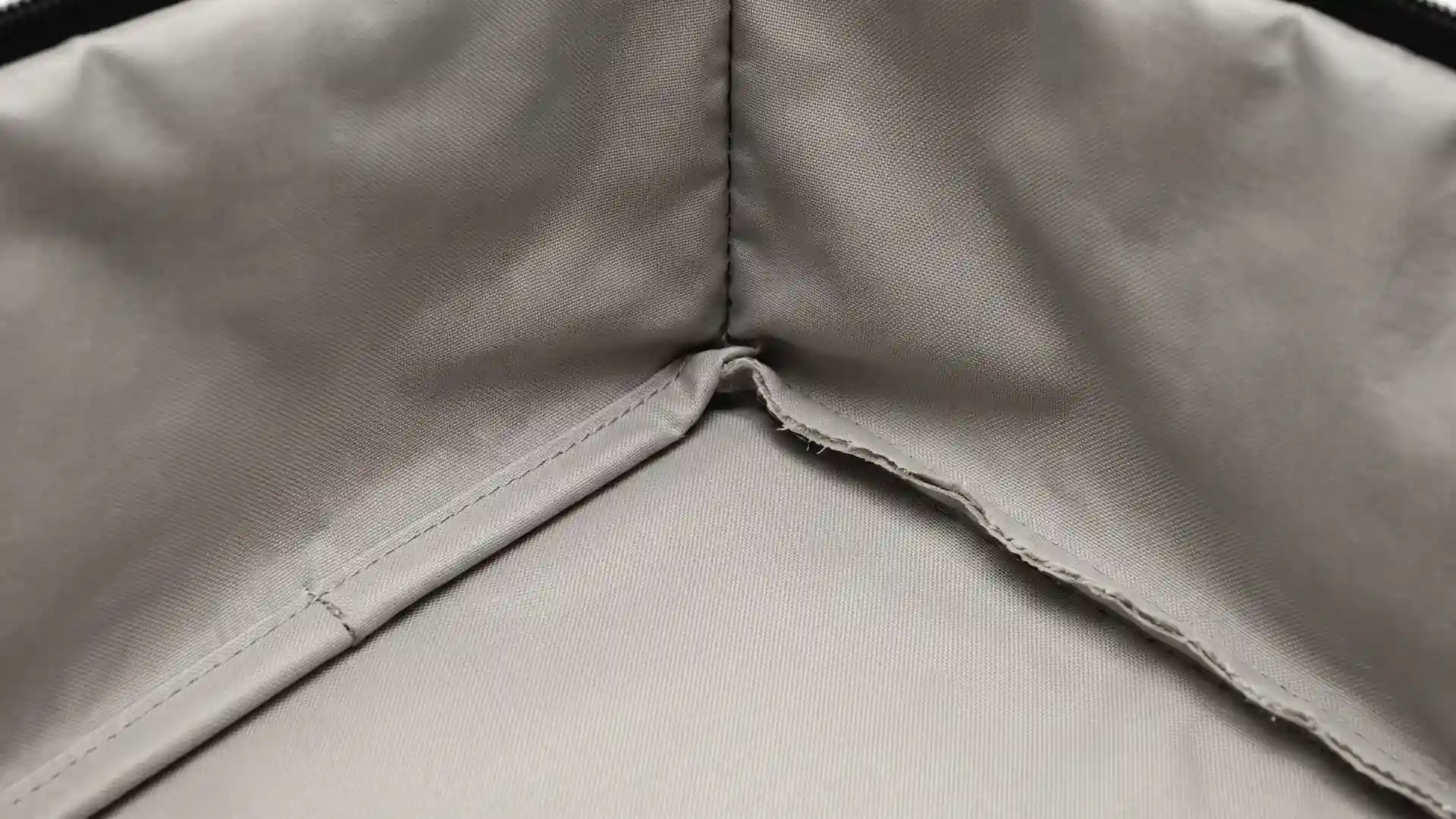 Close-up of an open medical organizer bag interior comparing a bound seam covering the raw lining edge with an exposed raw edge to show cleanability.